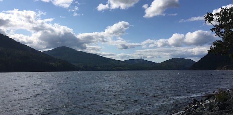 View of Alberni Inlet with mountains in the background and a cloudy sky above, showcasing the natural landscape of Vancouver Island.