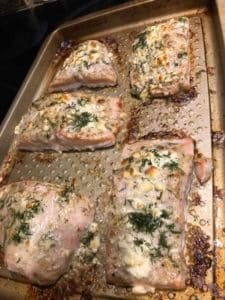 Cooked salmon fillets seasoned with herbs and spices on a baking tray, showing a golden-brown crust and flaky texture.