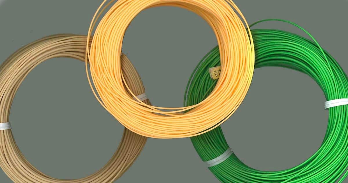 Three spools of fly fishing line in beige, yellow, and green colors arranged in a circular formation.