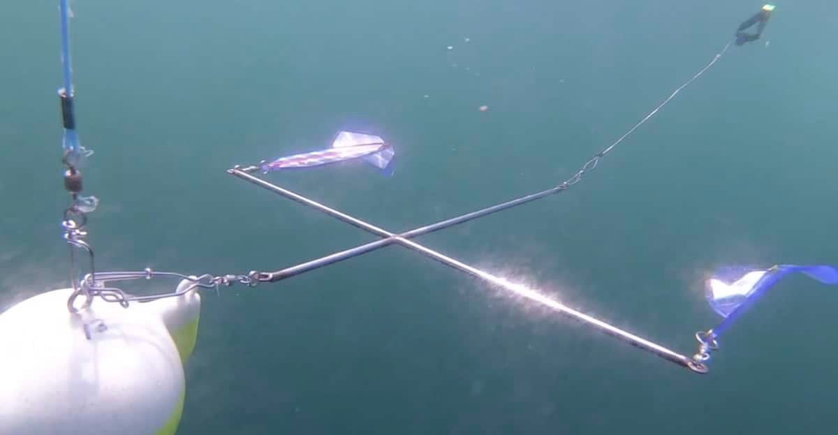 Underwater fishing gear with a cross-shaped rig and colorful flags attached, designed for attracting fish in aquatic environments.