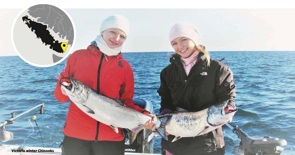 Two individuals holding large Chinook salmon while fishing on the water, wearing winter clothing and hats for warmth.
