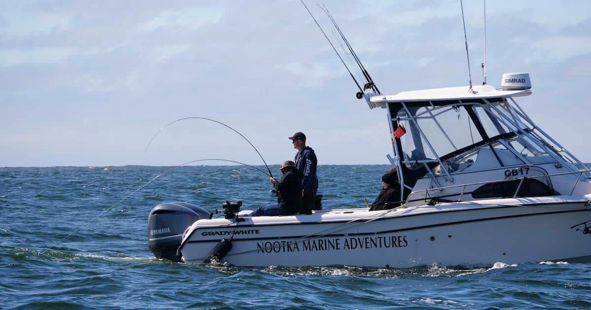 Fishing boat with two anglers casting lines into the ocean, marked with 'Nootka Marine Adventures' on the side.