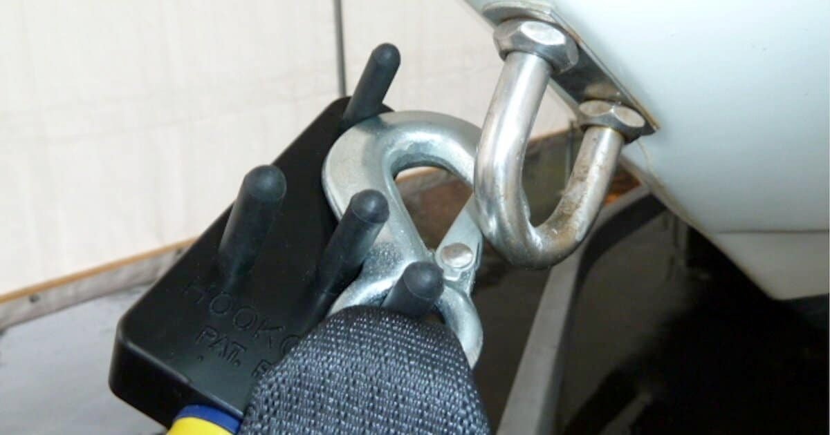 Boat retrieval tool with a metallic hook attached to a boat's cleat, designed for securing and retrieving boats.