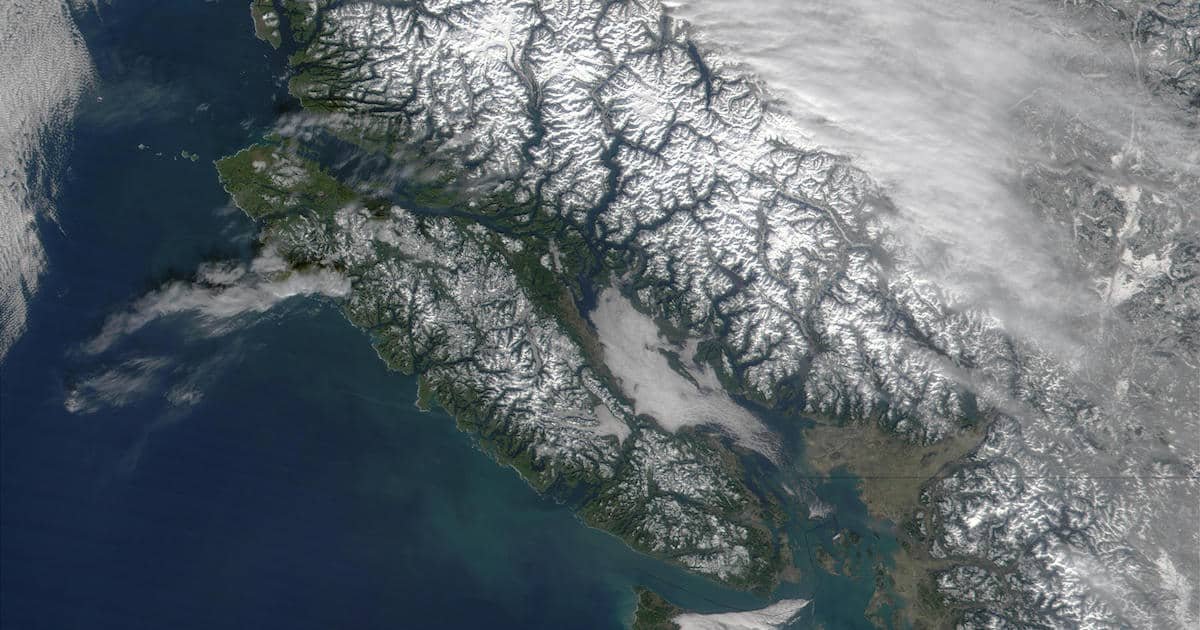 Satellite image of Vancouver Island, showcasing its mountainous terrain and coastal features with snow-capped peaks and surrounding waters.