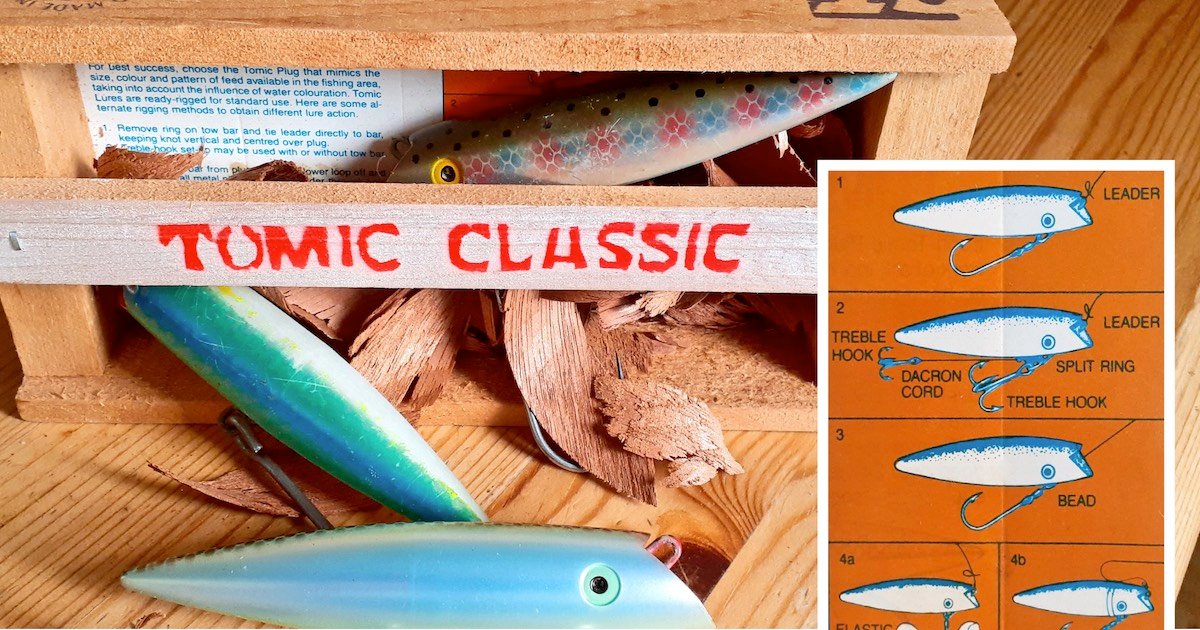 Tomic Classic fishing lures displayed in a wooden box, with a detailed diagram of lure components on the side.