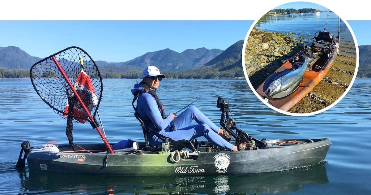 Person sitting in a kayak on calm water, holding a fishing rod with a net attached to the side.