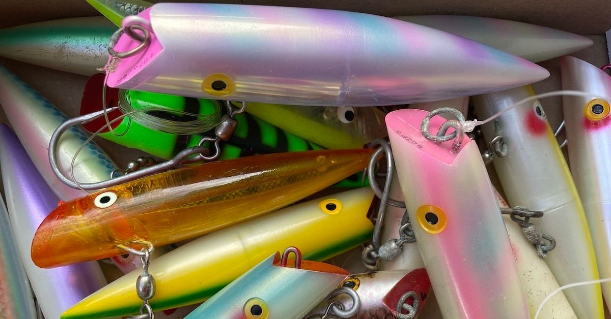 Assorted fishing lures in various colors and designs, including bright pink, orange, and yellow, arranged in a box.