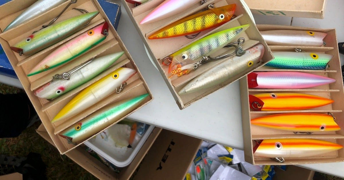 Collection of fishing lures arranged in boxes, showcasing various colors and designs, including bright and metallic finishes.