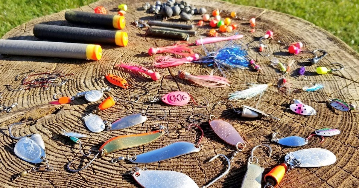Variety of fishing tackle including lures, hooks, and floats arranged on a wooden surface.