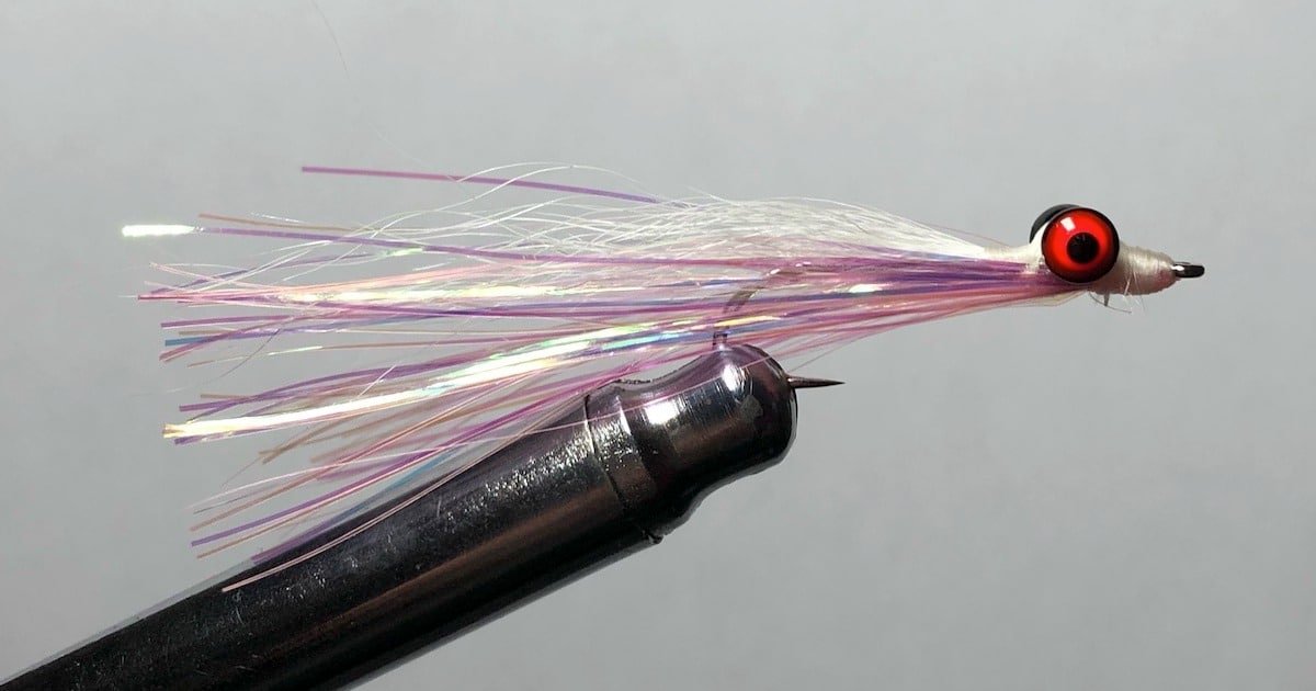 Coho Clouser fly tied with a white and purple synthetic material and a prominent red eye, mounted on a hook.