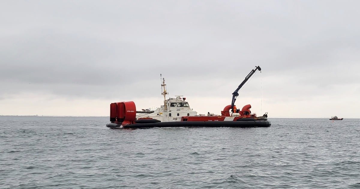 Hovercraft vessel with a red and white color scheme on water, equipped with a crane and additional equipment for marine operations.