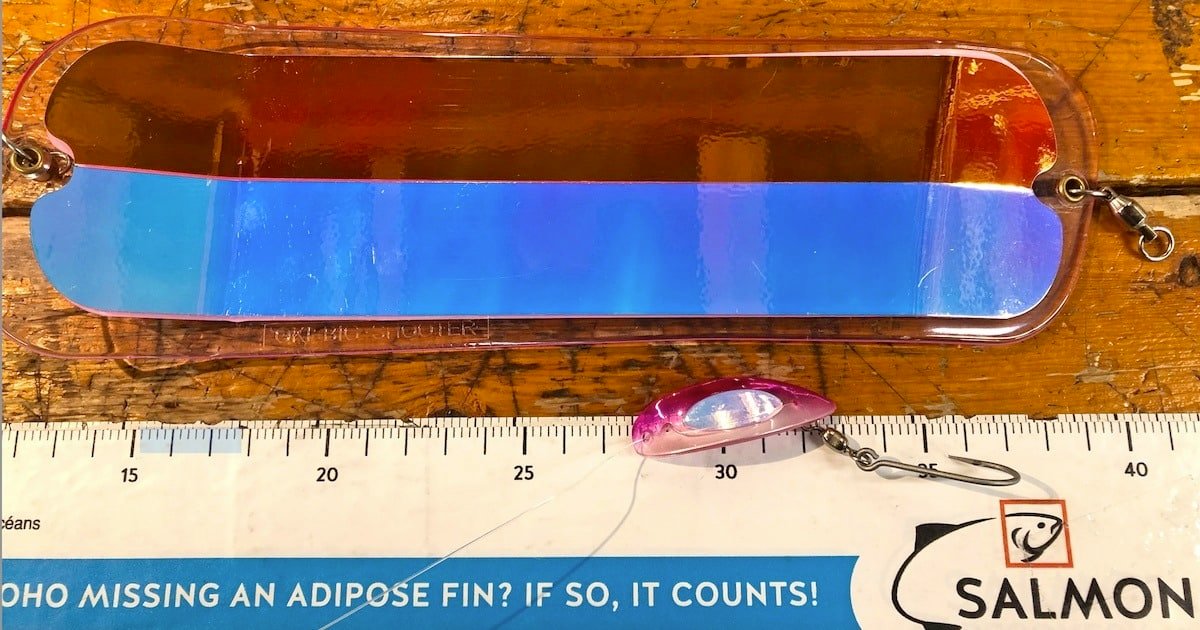 Colorful fishing lure with a reflective surface and a measuring ruler displaying a salmon fishing advertisement.