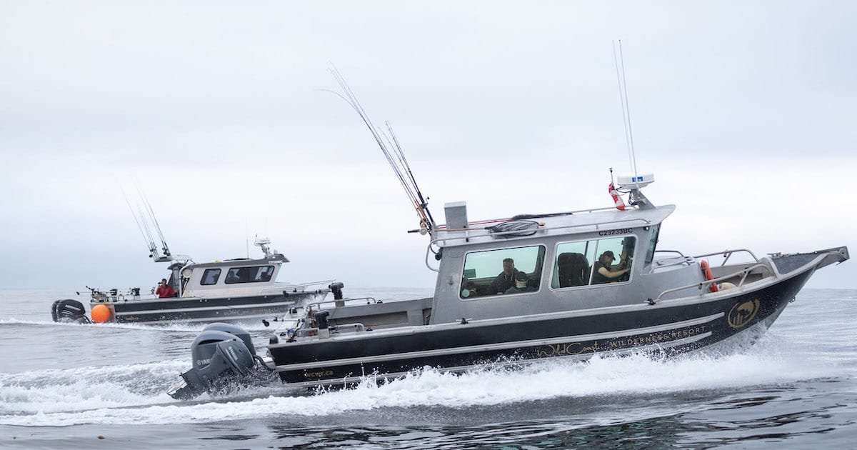 Two fishing boats navigating through calm waters, equipped with fishing rods and gear, creating waves as they move.