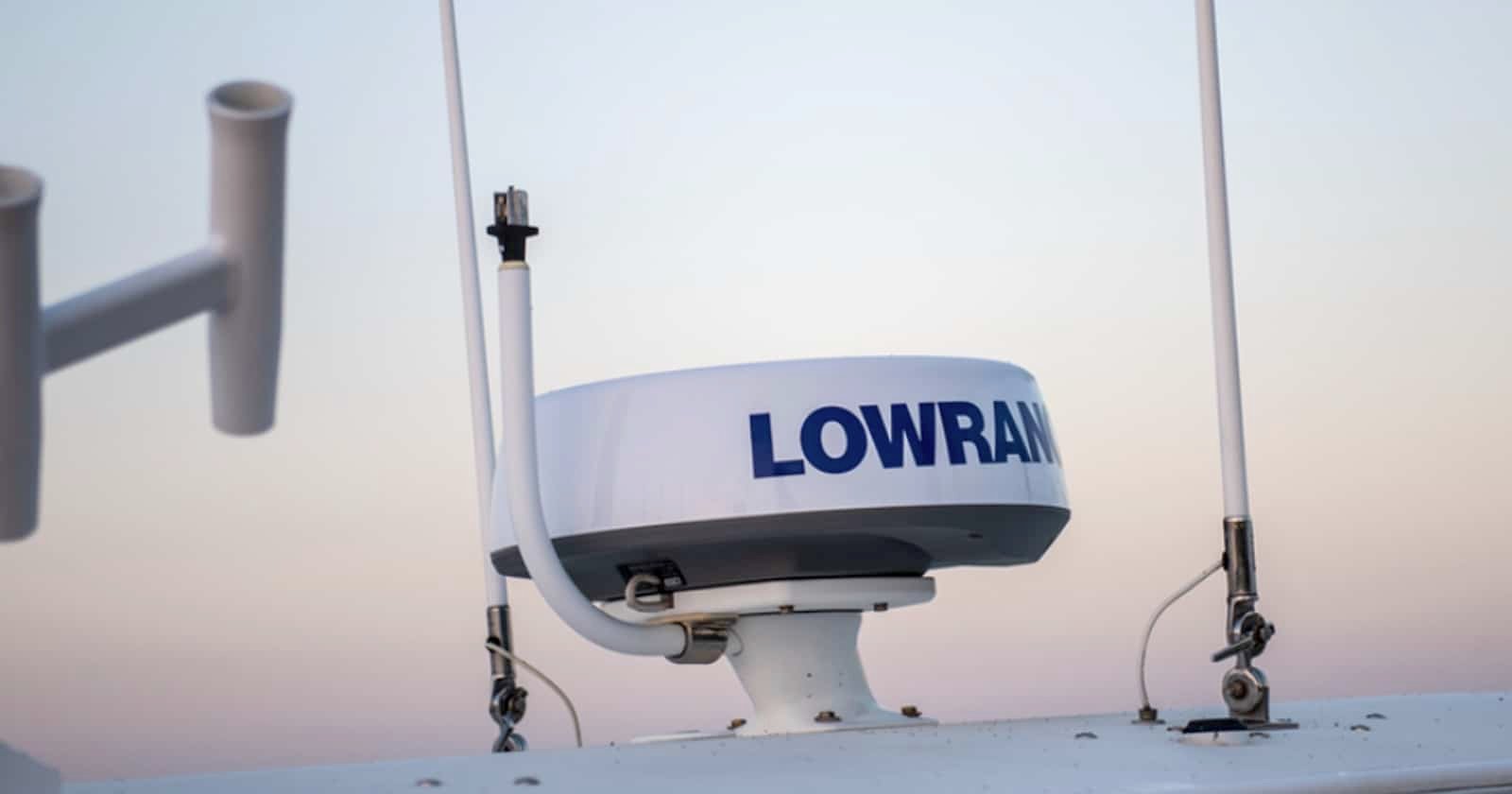 Marine radar system mounted on a pedestal on a boat, featuring the brand name 'LOWRANCE' prominently displayed.