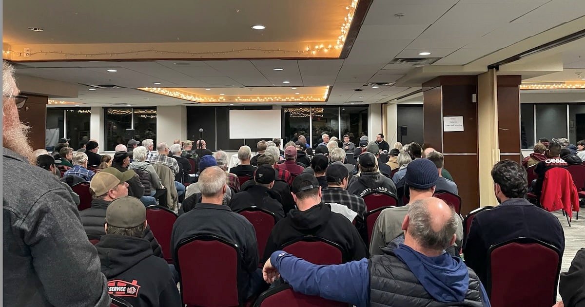 Audience gathered in a meeting room, attentively listening to speakers at a fisheries meeting with rows of chairs and a projector screen.