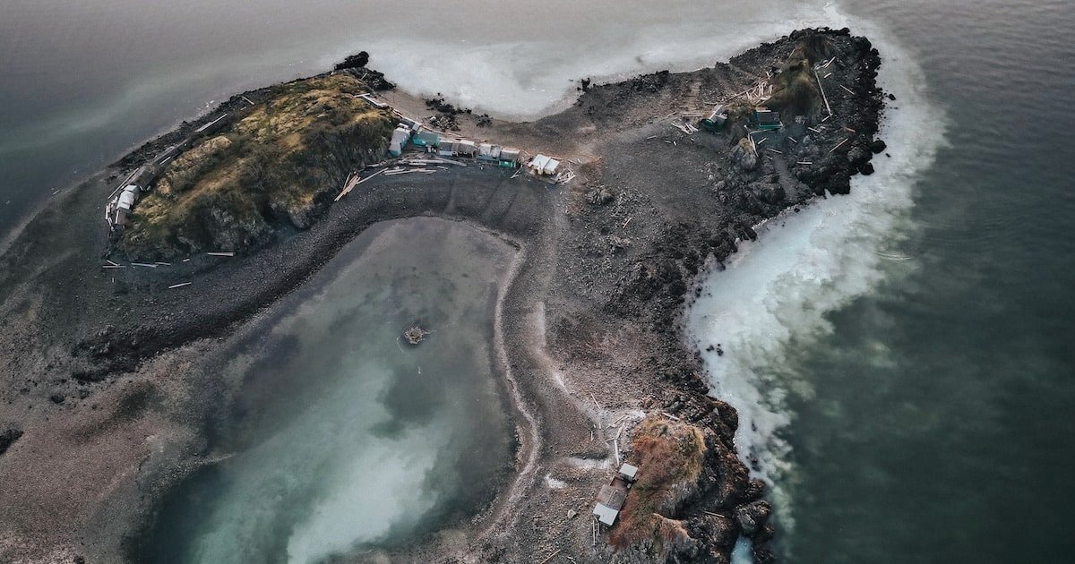 Aerial view of a coastal area featuring two small land masses with rocky shores and a shallow lagoon between them.