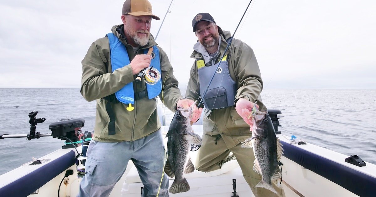 Two anglers on a boat holding black rockfish caught during a fishing trip in the ocean.