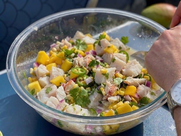 A vibrant bowl of fresh Halibut Ceviche featuring cubed white fish, bright mango, red onion, and cilantro in a citrus marinade.